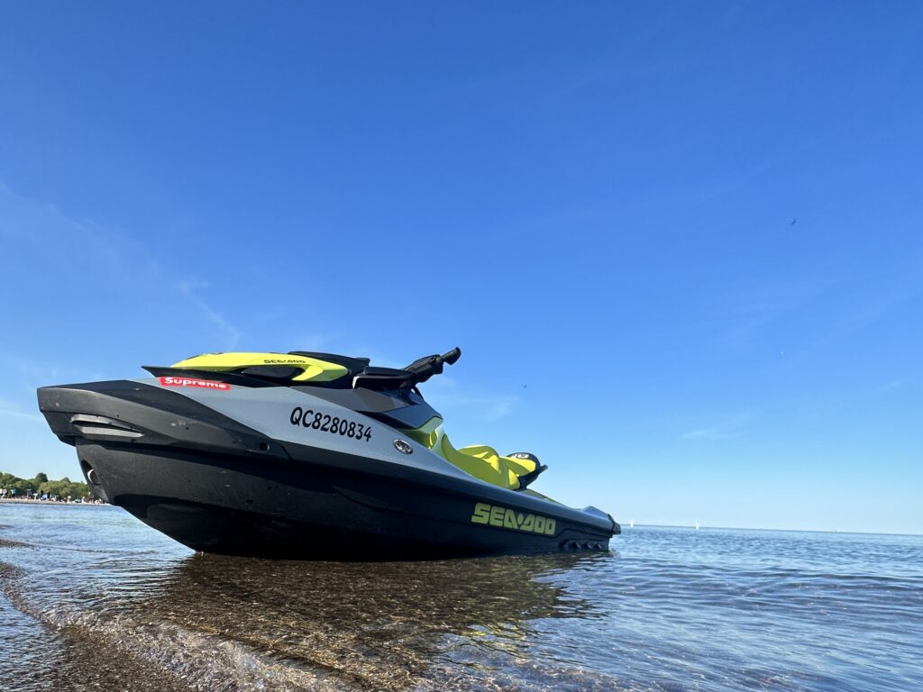 A jet ski from JetSkiGTA gliding on Lake Ontario with the Toronto skyline and CN Tower in the background.