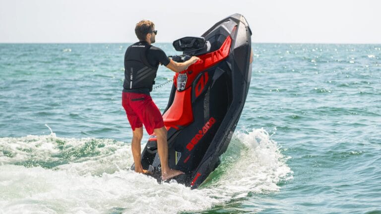 Two people riding Seadoo jet skis on Lake Ontario with the Toronto skyline in the distance, starting from Scarborough Bluffers Park and heading toward Woodbine Beach.