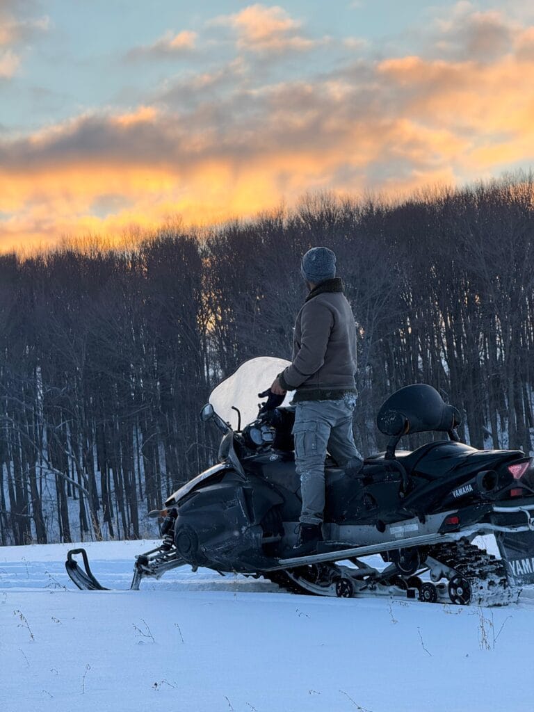 snowmobile rentals on a a snow filled farm looking over sunset