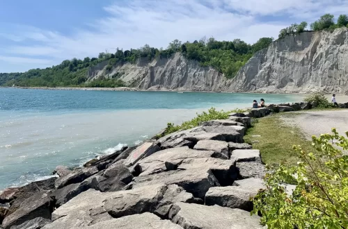 A stunning view of Scarborough Bluffers Park Beach with calm waters, boats, and jet skis ready for rental on a sunny day.