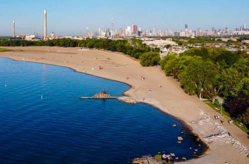 A vibrant scene at Woodbine Beach with jet skis and boats ready for rental, set against the sparkling waters of Lake Ontario and a lively summer crowd.